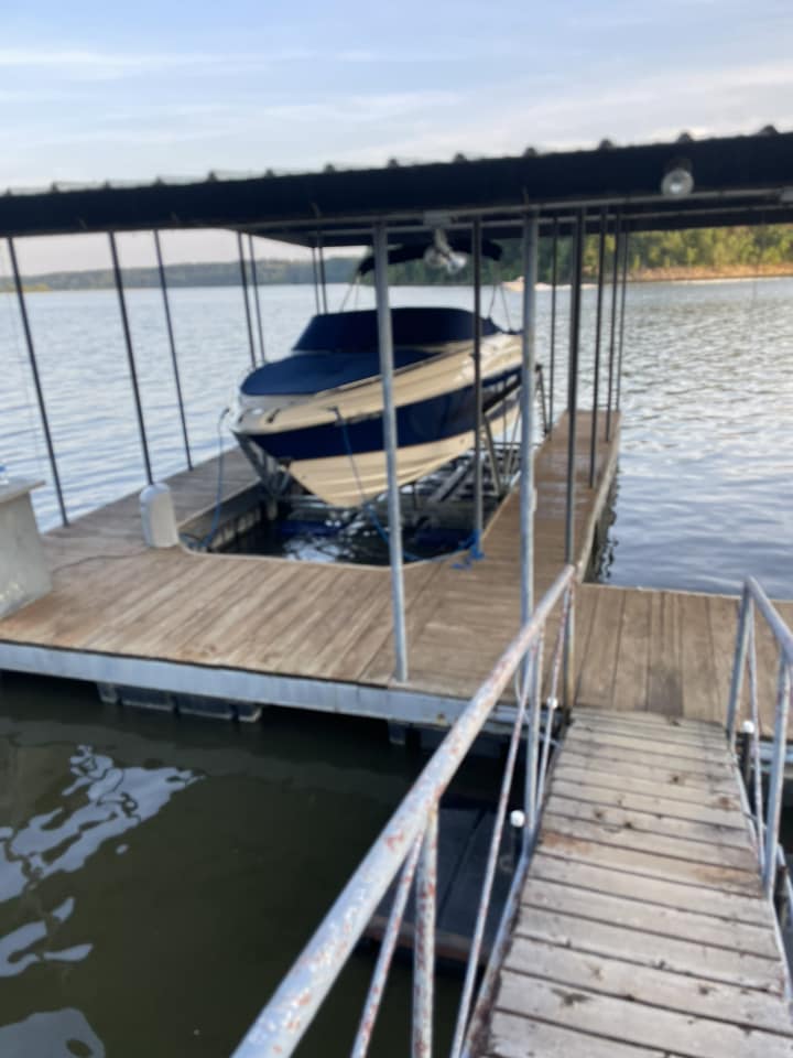 Covered boat dock with a boat lift and wood decking on Grand Lake Oklahoma, viewed from the walkway