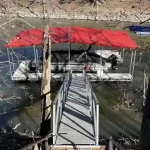 Covered boat dock with a red canopy and sloped gangway on Grand Lake in Oklahoma